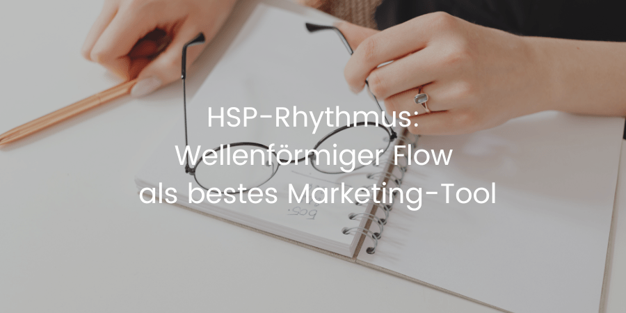Coverbild zum Blogbeitrag: HSP-Rhythmus-Strategie. Eine Hand hält eine Brille über einem Notizbuch mit dem Titel: Warum dein wellenförmiger HSP-Rhythmus das beste Tool für Business und Content ist.
